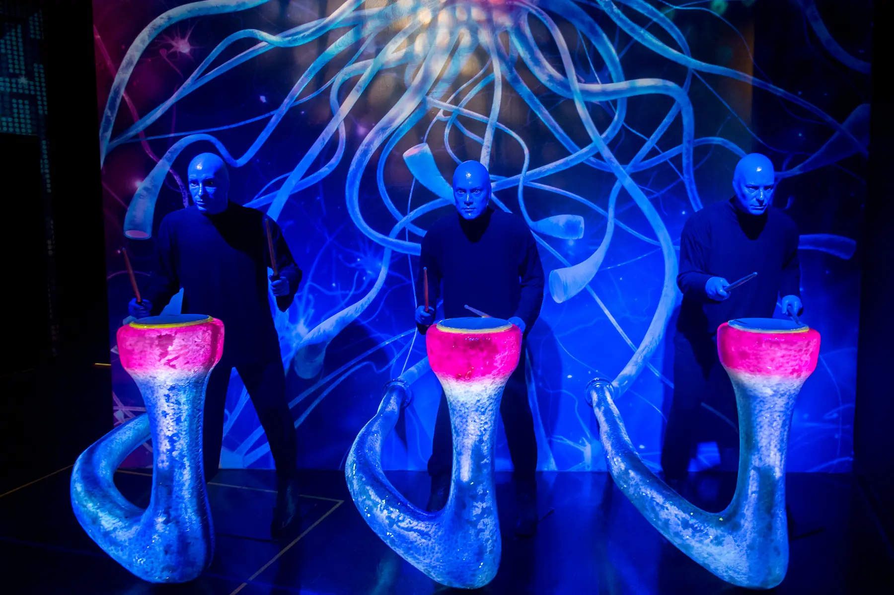 Blue Man Group performs in Las Vegas, creating a visually stunning show with glowing drums and a surreal blue-lit backdrop. Known for their mix of music, comedy, and technology, the trio is one of the most iconic Las Vegas shows.