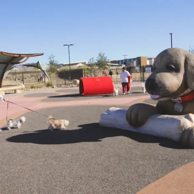 Dog park in Henderson Nevada with giant statue of a friendly dog greeting a woman and her dog.